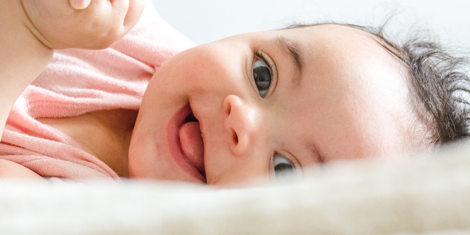 Bébé souriant allongé, éveillé et curieux, en gros plan